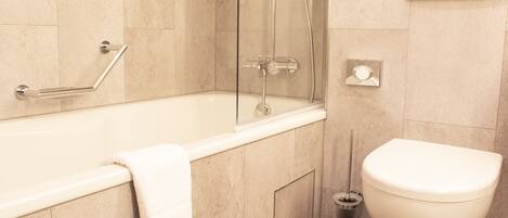 A modern bathroom with a bathtub, toilet, and shower.