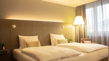 Une chambre d’hôtel avec deux lits, une table de chevet, une lampe et une chaise.