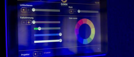 Panel de control con opciones de iluminación y configuración de color, etiquetado como 'KONFERENZRAUM 2' y 'GINN HOTEL'.