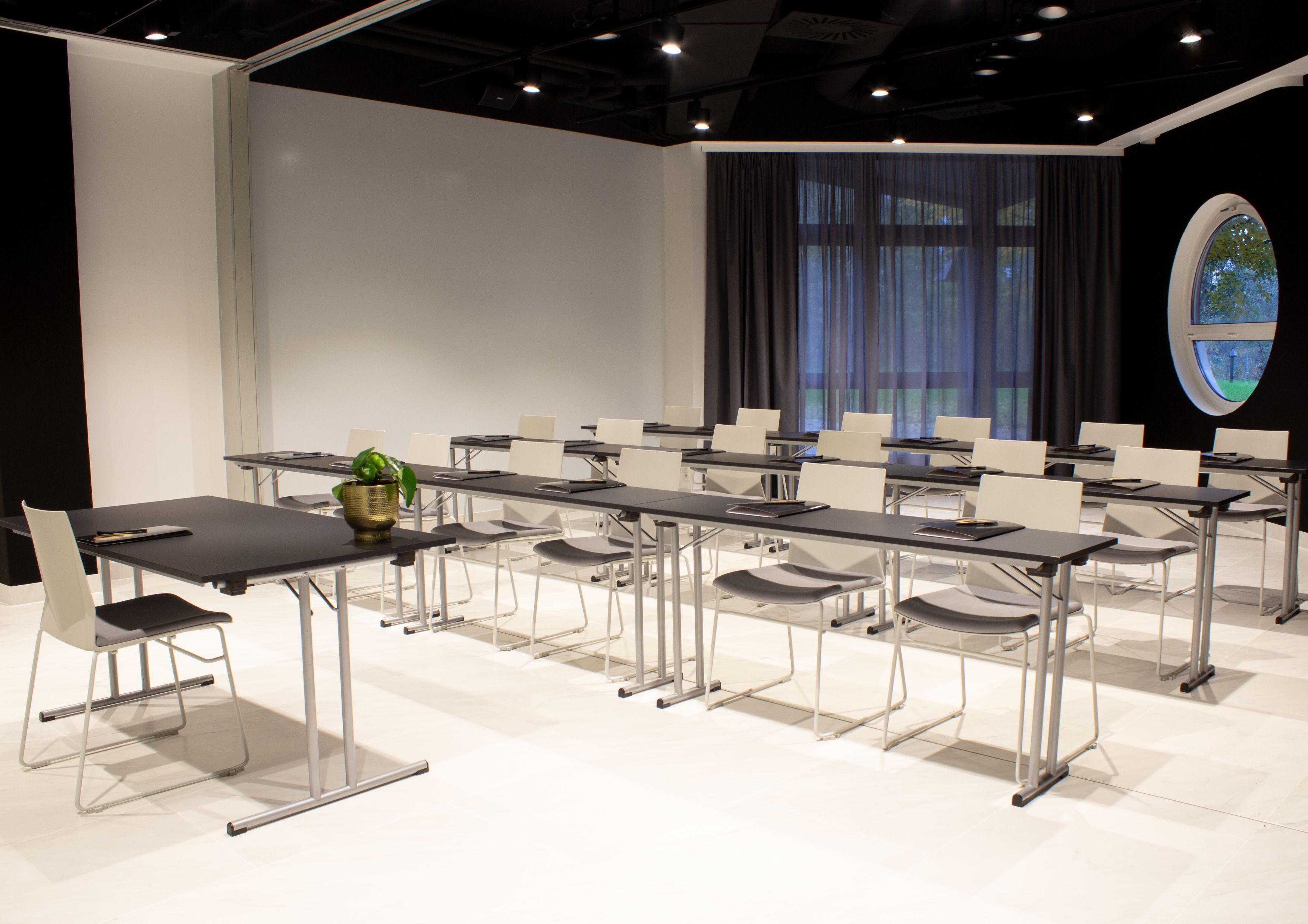 Ein Konferenzraum mit einem langen Tisch, Stühlen und einer Zimmerpflanze.