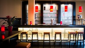 Eine Bar mit einer Theke, Hockern und Regalen mit Gläsern.