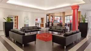 Eine moderne Lobby mit schwarzen Sofas, einem roten Teppich und einem Glastisch.