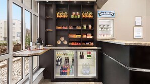 Ein Verkaufsbereich mit Regalen voller Snacks und Getränke, einer Kaffeemaschine und einem Getränkekühlschrank.