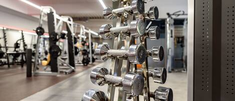 Une salle de sport équipée de divers appareils d’exercice, notamment des haltères et des machines de musculation.