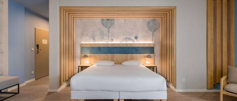 A bedroom with a bed, bedside tables, a headboard with a tree mural, and a wooden floor.