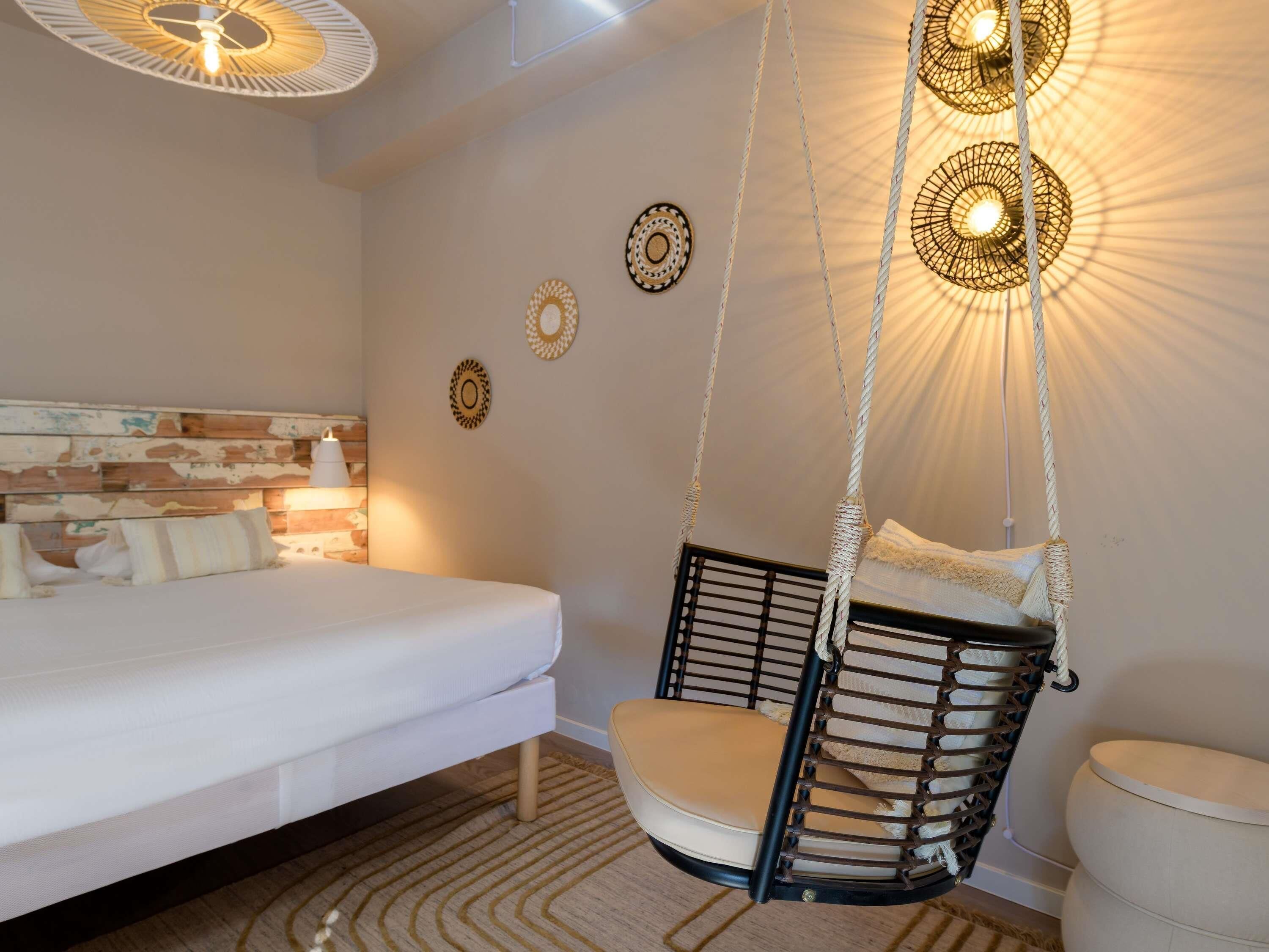 A bedroom with a bed, a hanging chair, a bedside lamp, and decorative wall plates.
