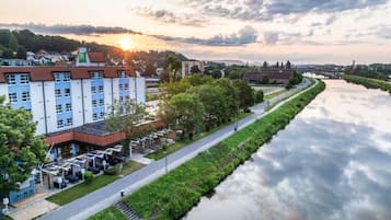 Ein Hotel am Flussufer mit einem langen Gebäude, einem gepflasterten Weg und einem ruhigen Fluss.