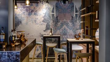 A bar area with a rustic design, featuring wooden furniture, a patterned wall, and hanging lights.