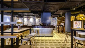Zona de bar moderna con suelo a cuadros, mobiliario de madera y una barra central.