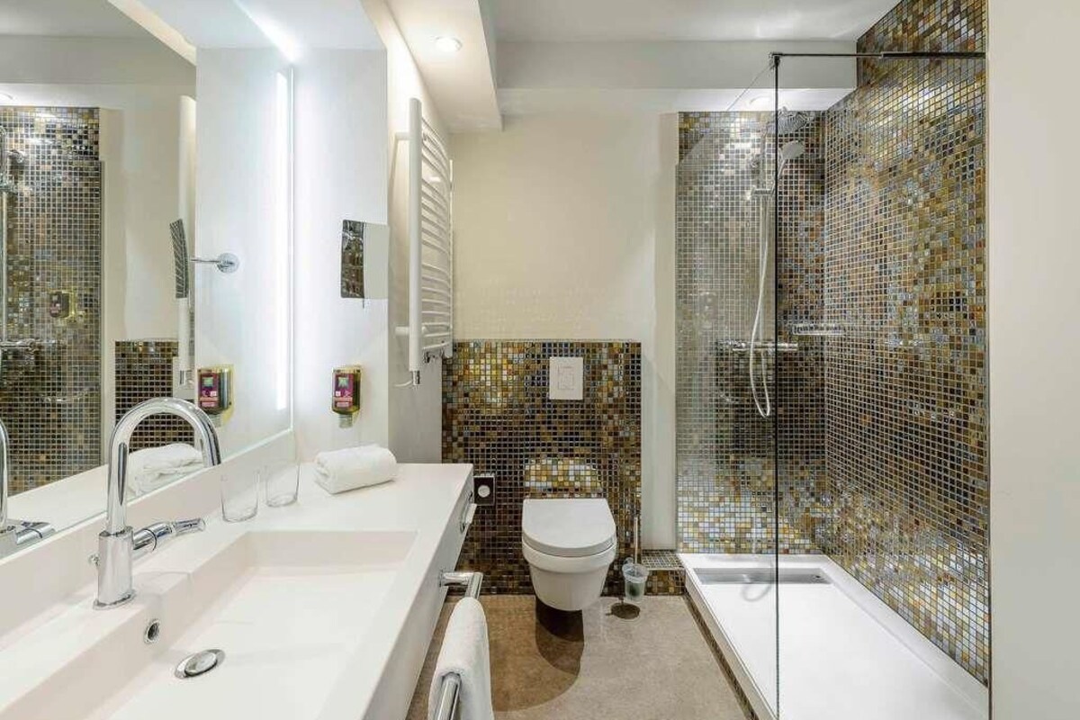 Een moderne badkamer met een grote spiegel, twee wastafels, een toilet en een douche met glazen wanden.