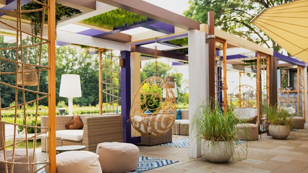 Un espacio de patio al aire libre con asientos, una silla colgante y plantas en macetas.