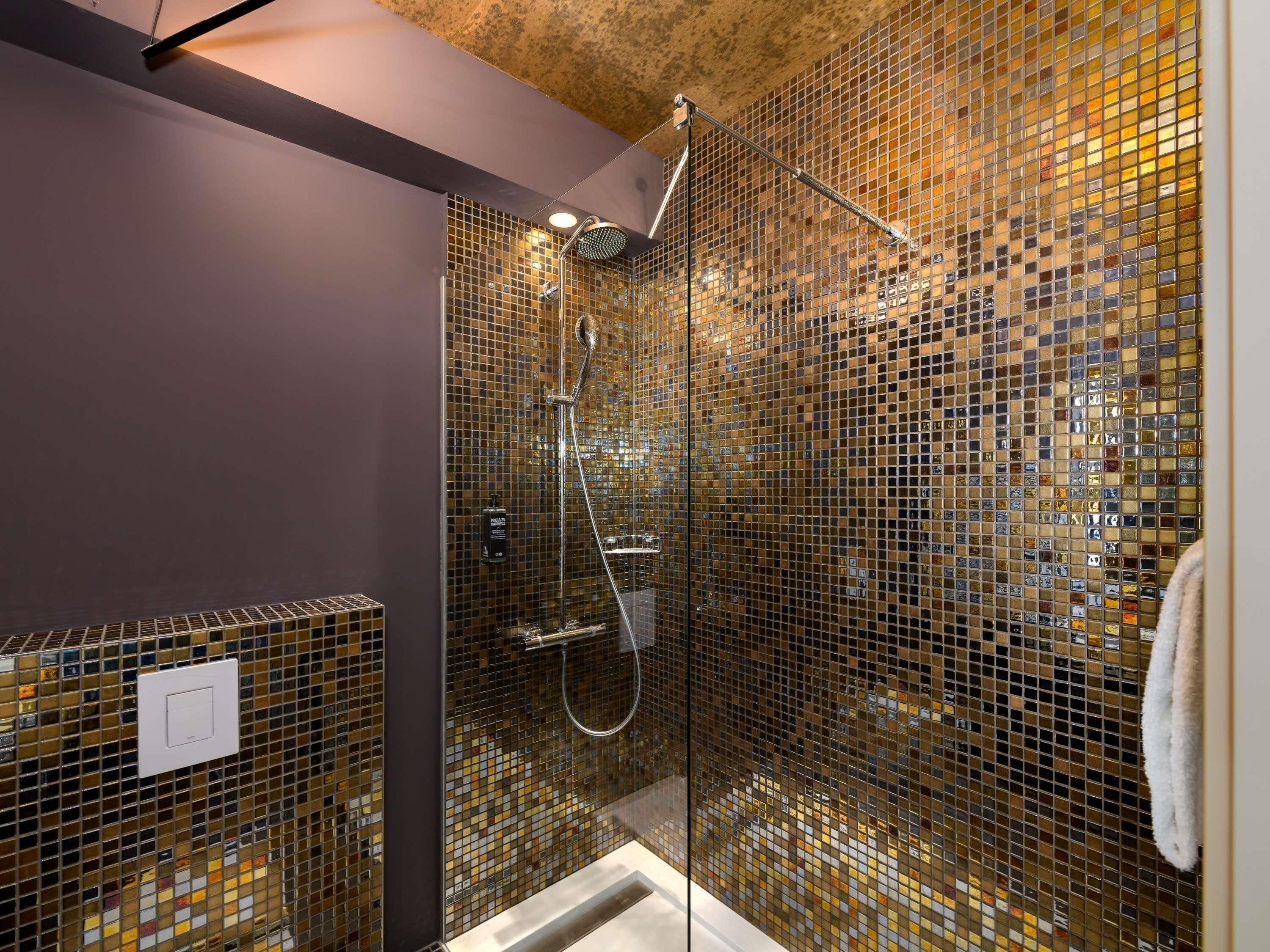 A shower with a glass enclosure, a handheld showerhead, and a wall-mounted control panel.
