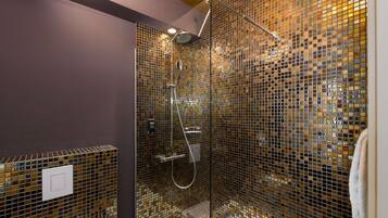 A shower with a glass enclosure, a handheld showerhead, and a wall-mounted control panel.
