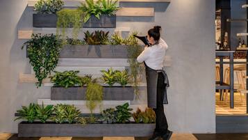 A modern interior with a vertical garden wall, wooden steps, and a person using a device.