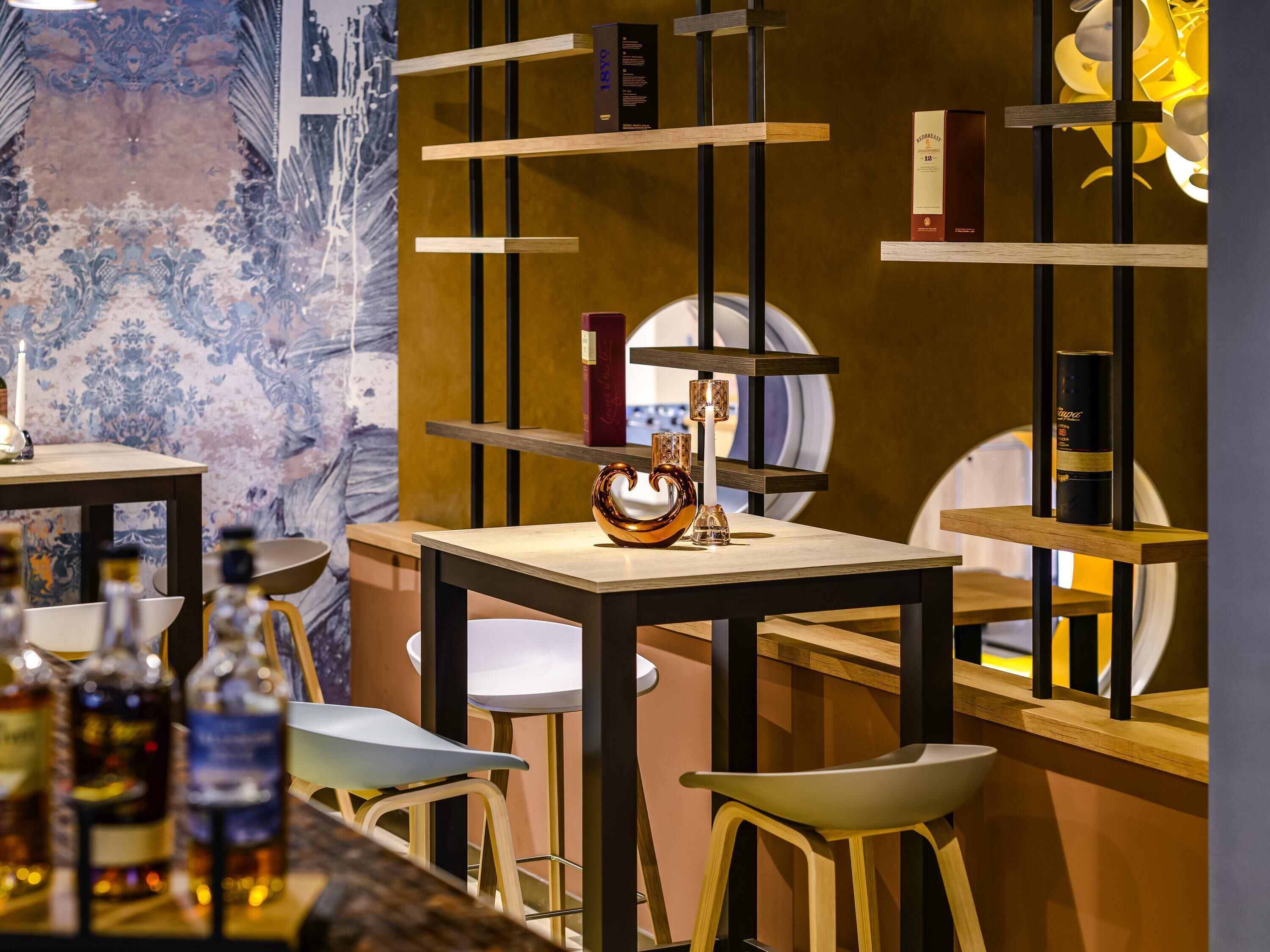 A bar area with stools, shelves with bottles, and a decorative wall.