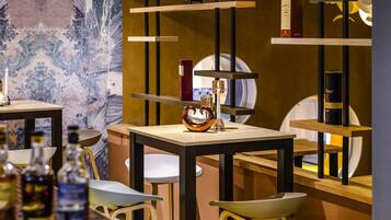 A bar area with stools, shelves with bottles, and a decorative wall.