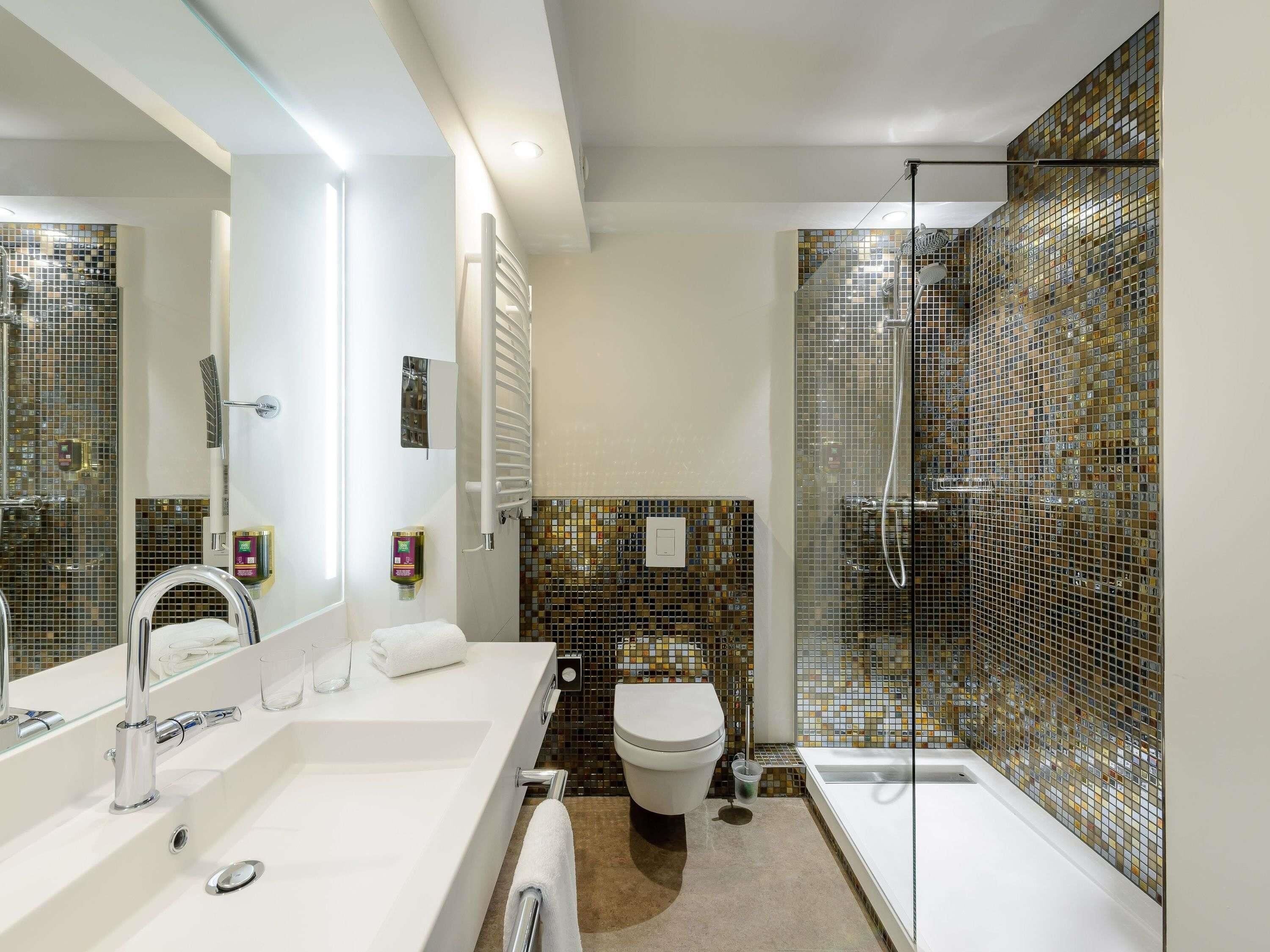 A bathroom with a white sink, a toilet, a shower with a glass door, and a mirror.