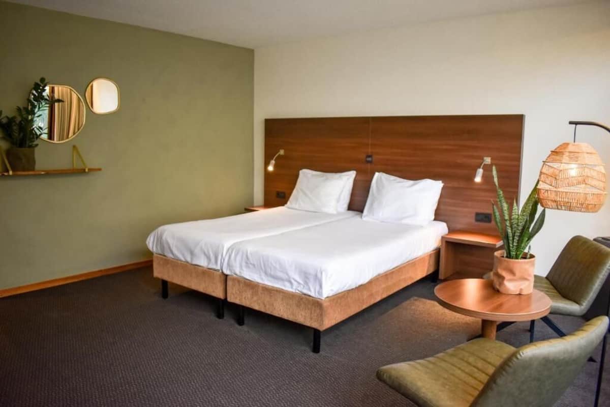 A hotel room with a large bed, bedside tables, a round coffee table, and a chair.