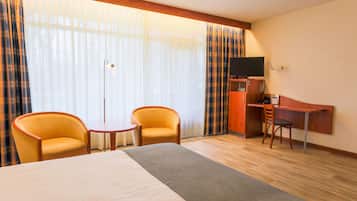 Habitación de hotel con cama, dos sillones, una mesita, un escritorio, televisión y armario.