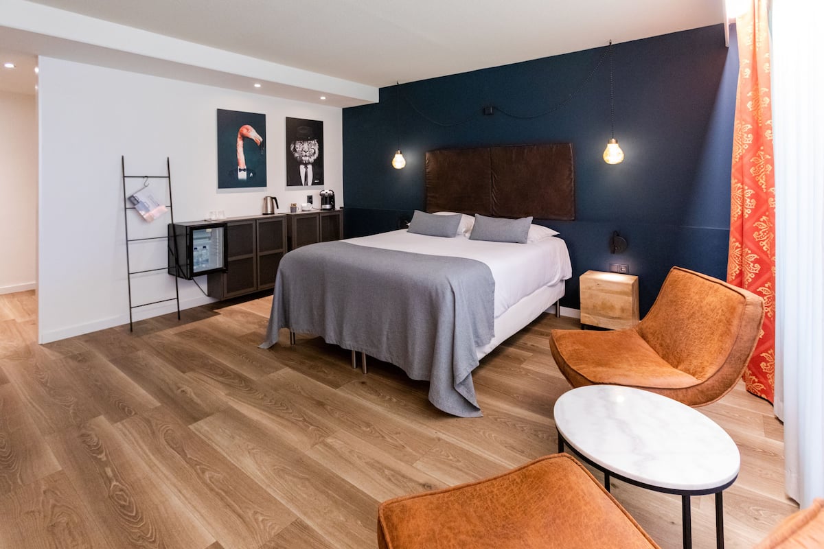 A modern bedroom with a large bed, bedside tables, a desk, and a chair.