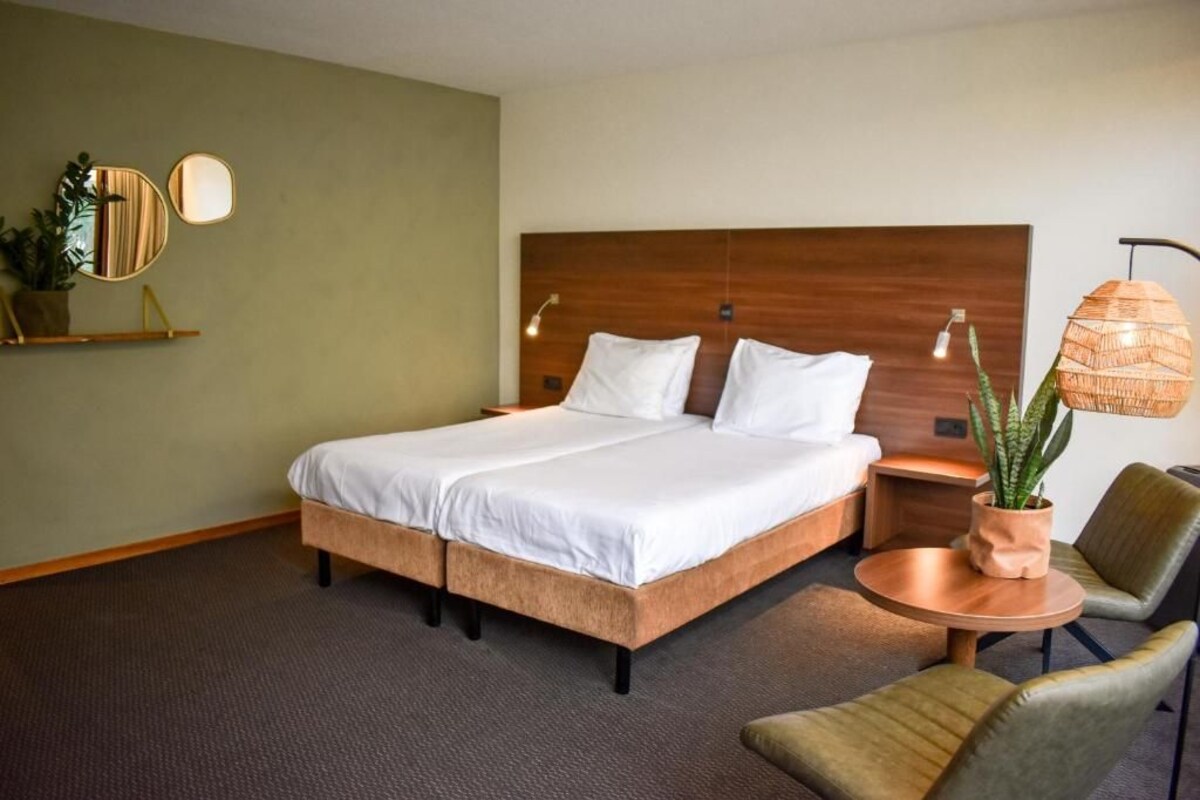 A hotel room with a large bed, bedside tables, a round coffee table, and a chair.