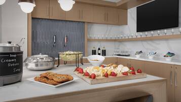 A modern kitchen with a buffet setup, including a variety of food items and a beer tap.