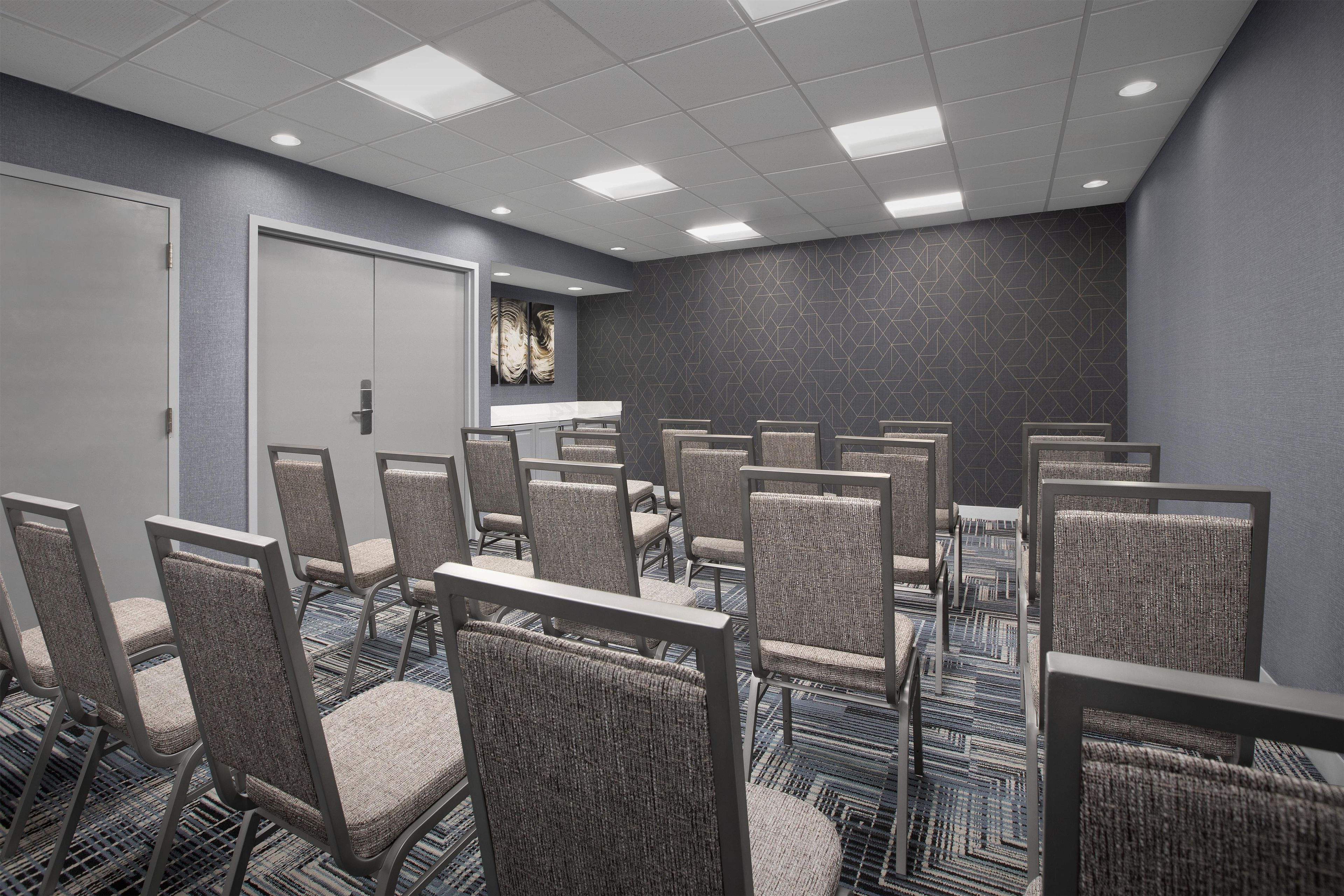 A conference room with rows of chairs, a whiteboard, and a door.