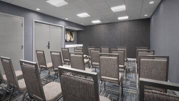 A conference room with rows of chairs, a whiteboard, and a door.
