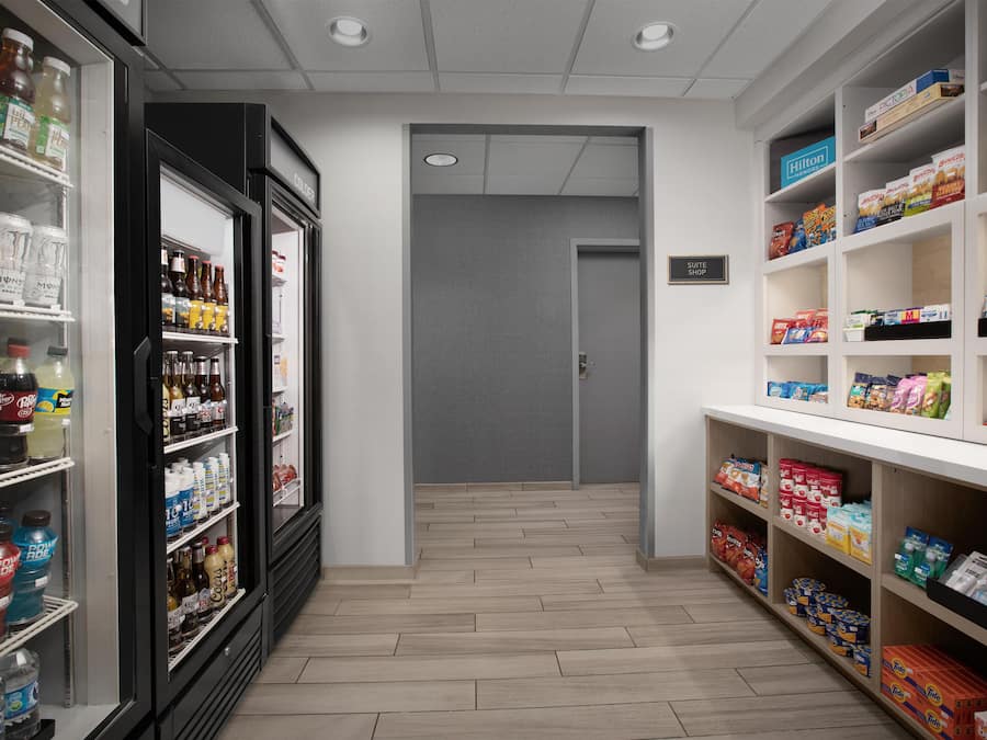A hotel corridor with a minibar, snack shelves, and a sign for the suite shop.
