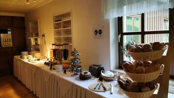 Ein reichhaltiges Buffet mit verschiedenen Speisen und Besteck auf einer Tischplatte, umgeben von Regalen mit Glaswaren und einem Fenster mit Blick.
