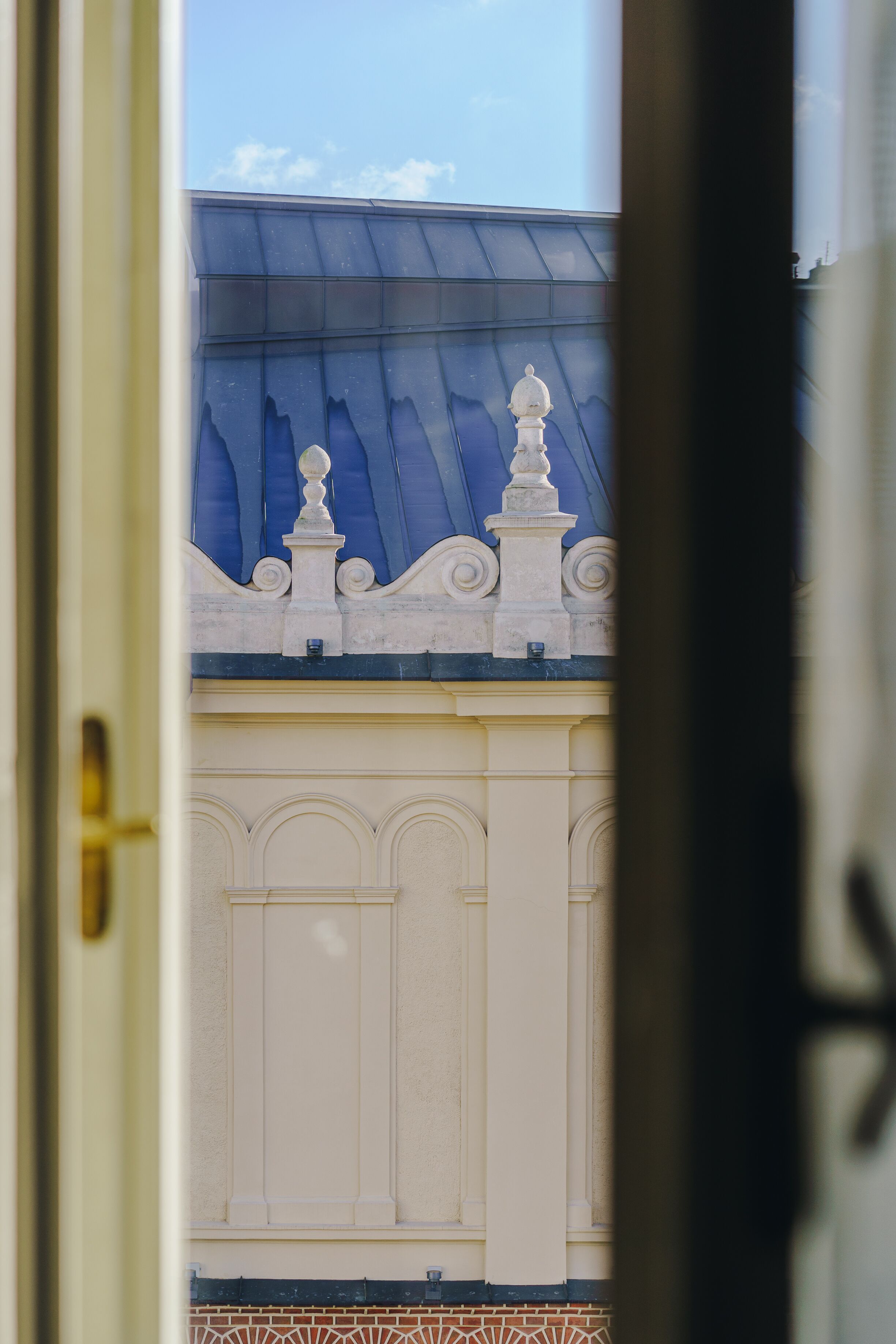 Une vue à travers la porte d’un bâtiment, montrant son aspect extérieur, avec un toit bleu et des éléments décoratifs blancs.