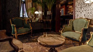 Una habitación lujosa con sillones tapizados en verde decorativo, una mesa de centro de mármol y una alfombra estampada.