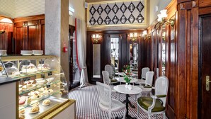 Un comedor con una vitrina de postres, sillas blancas tapizadas y un suelo estampado.