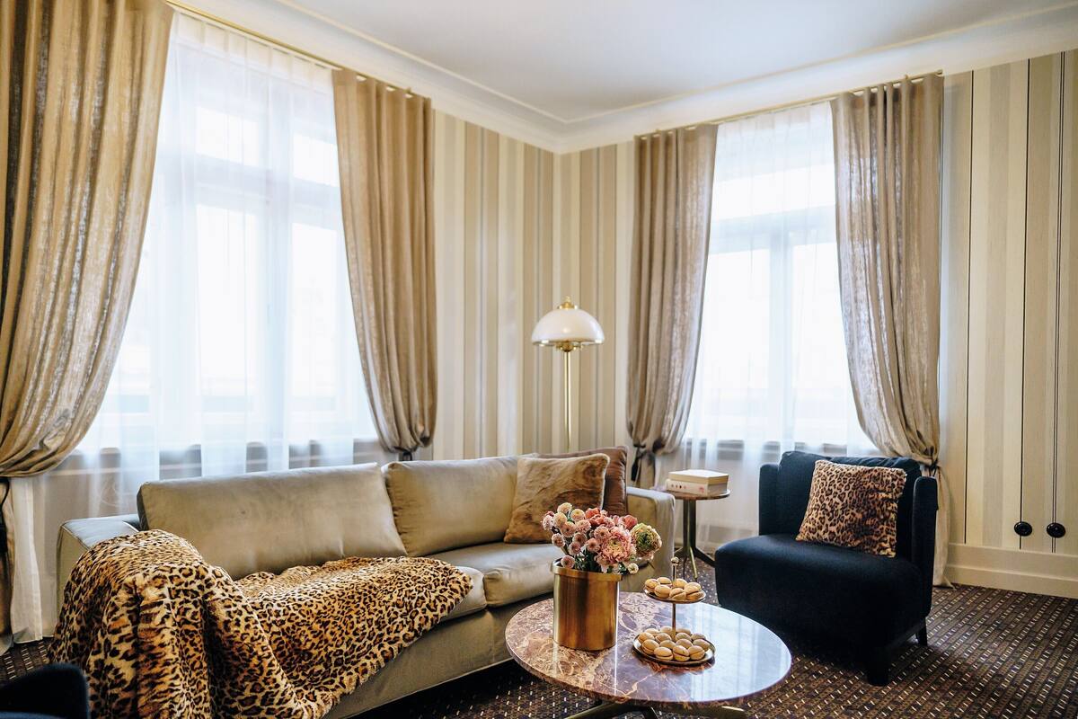 A living room with a sofa, armchair, coffee table, and curtains.
