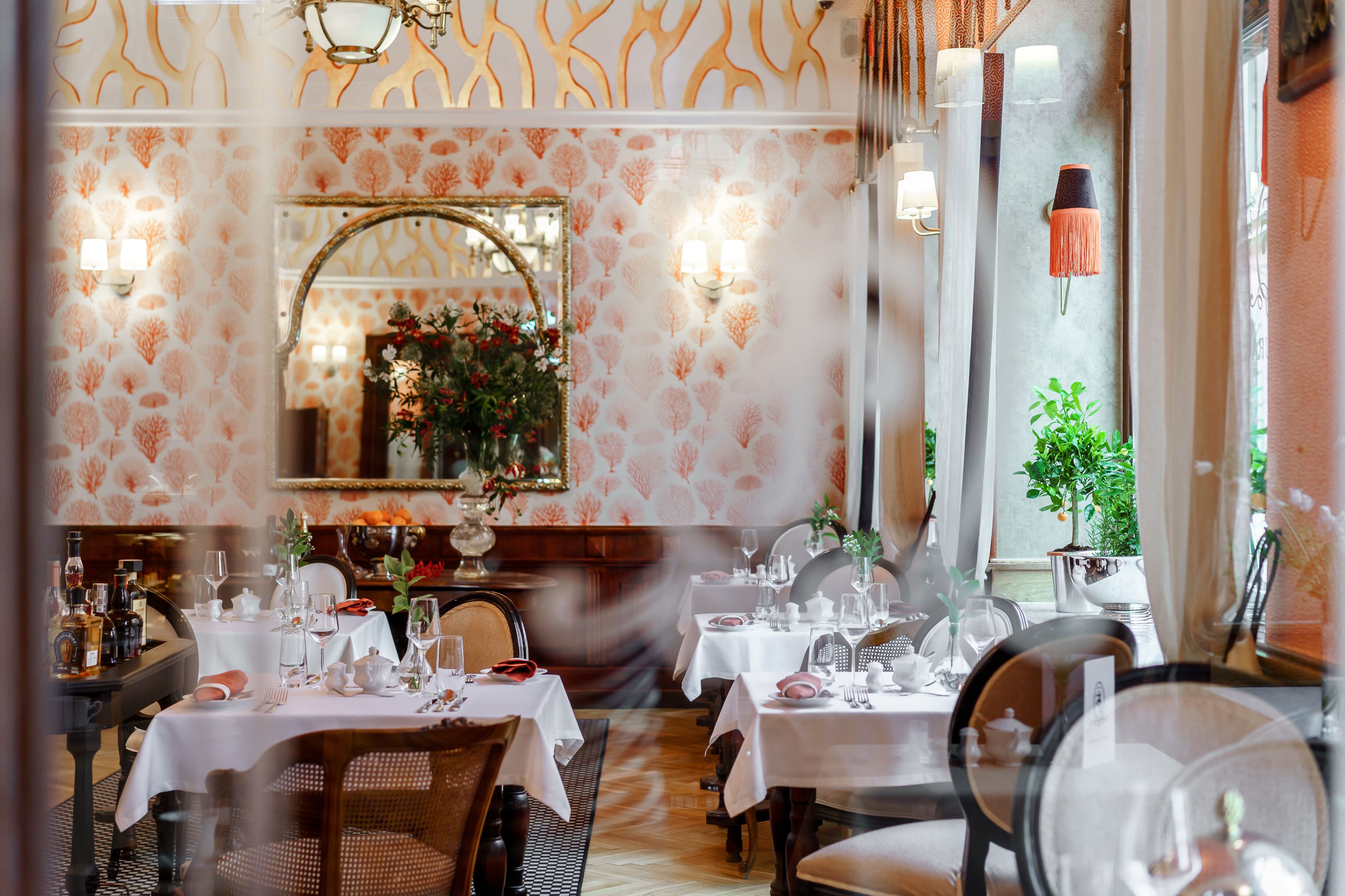 Een restaurant met gedekte tafels, een spiegel en wandlampen.
