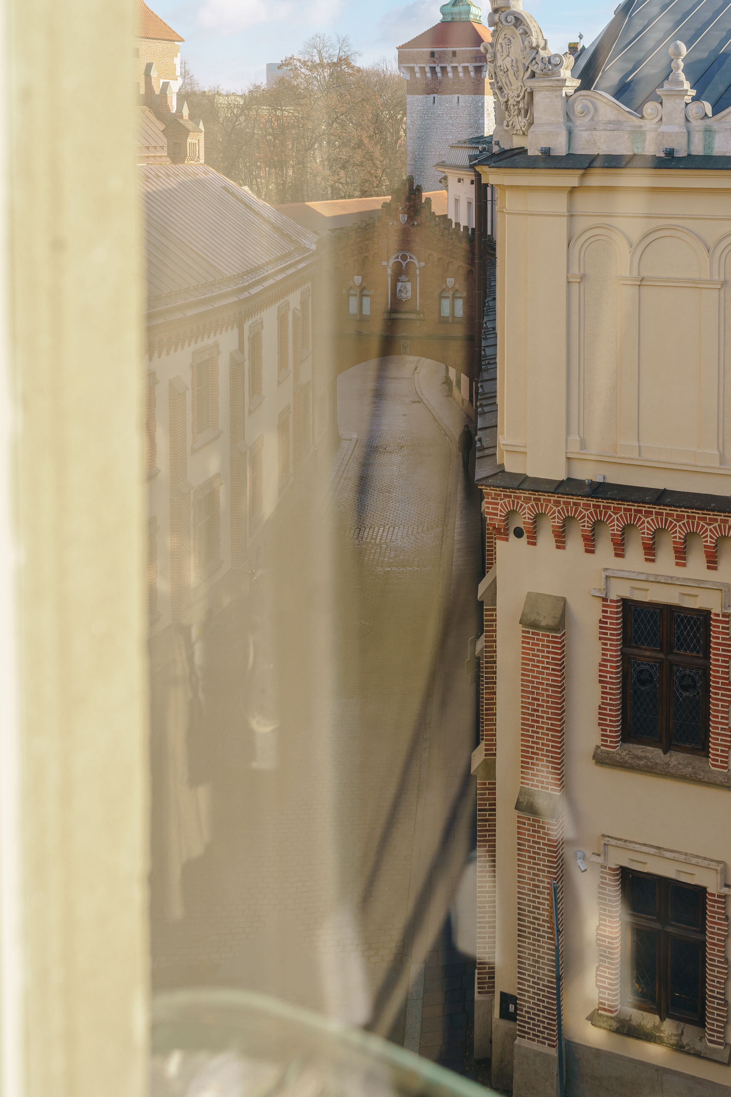 A narrow street with buildings on either side, featuring traditional architecture with brick facades and ornate details.