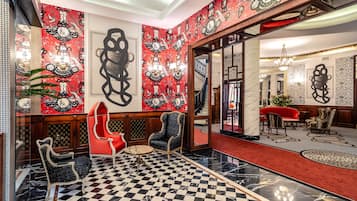 A lobby with a checkered floor, red and black patterned walls, and a red sofa.