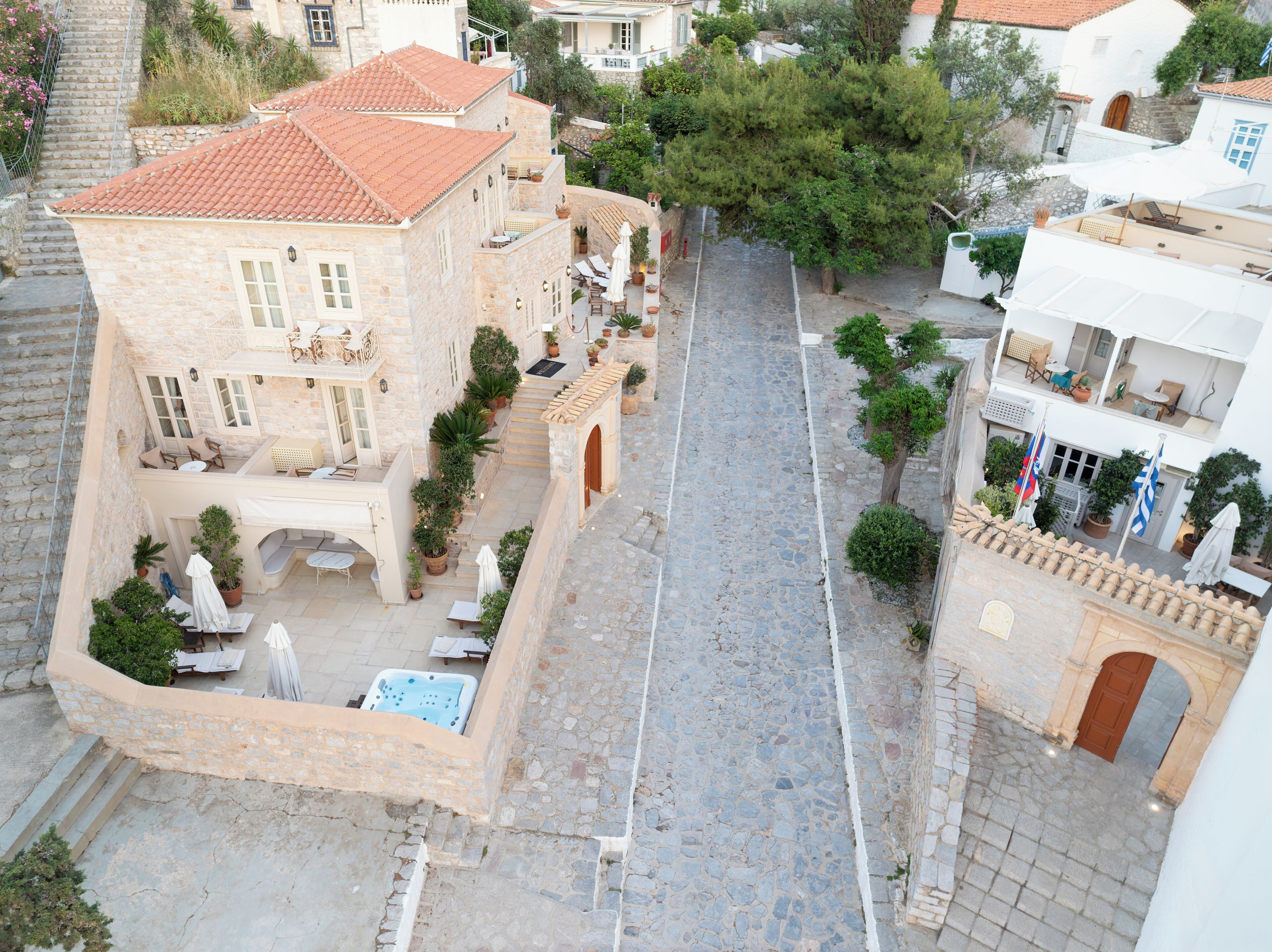 A courtyard with stone flooring, potted plants, outdoor seating, and a hot tub.