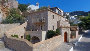 A stone building with a balcony, a staircase, and a view of the surrounding area. - Angelica Boutique Hotel (Hydra)