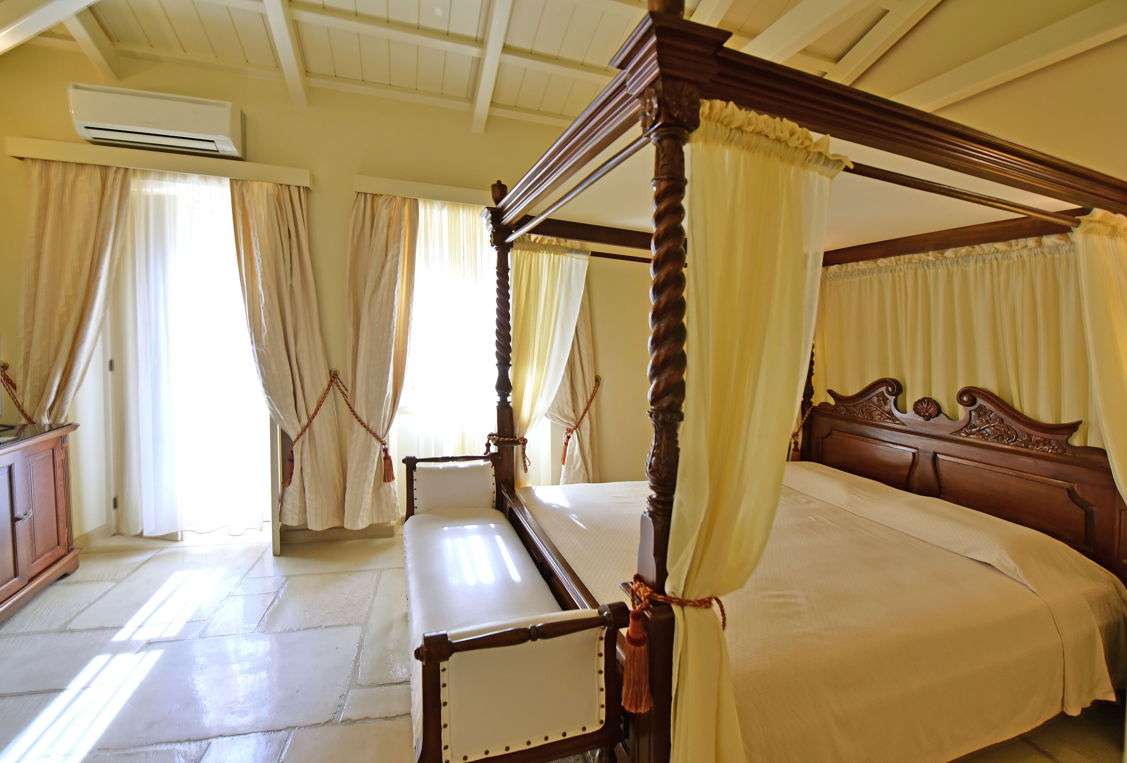 A four-poster bed with a canopy, a wooden headboard, and a bedside table.