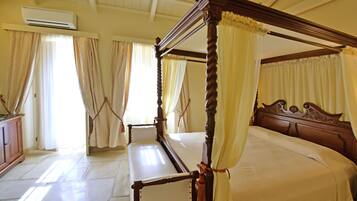 A four-poster bed with a canopy, a wooden headboard, and a bedside table.