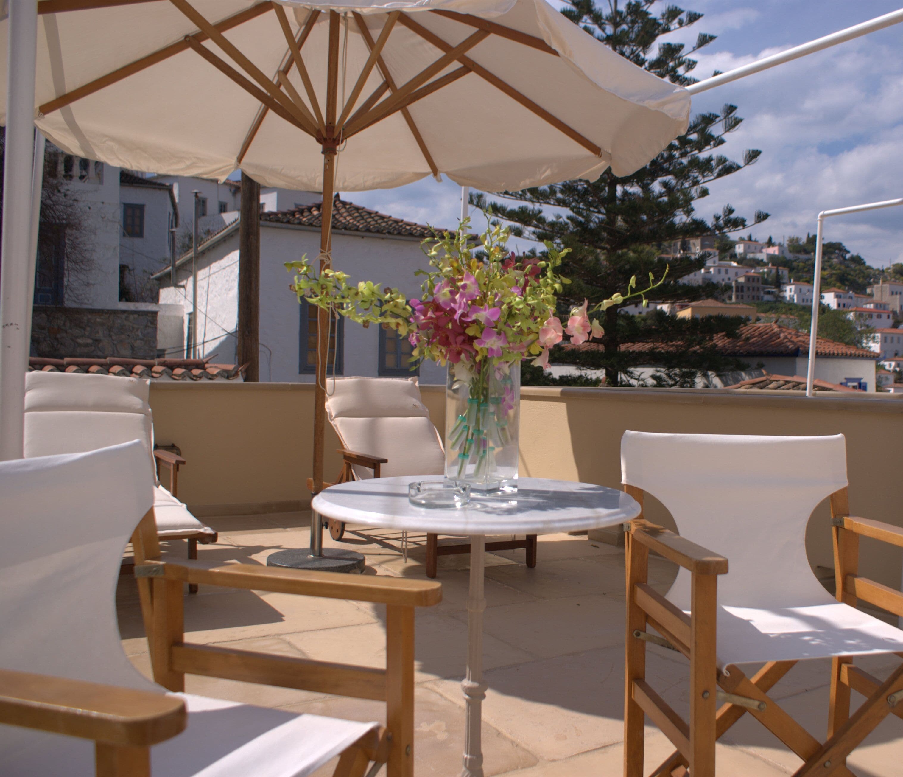 Una terraza con una mesa redonda, sillas y un florero.