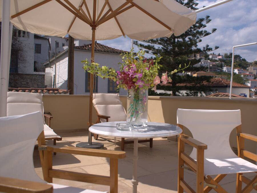 Una terraza con una mesa redonda, sillas y un florero.