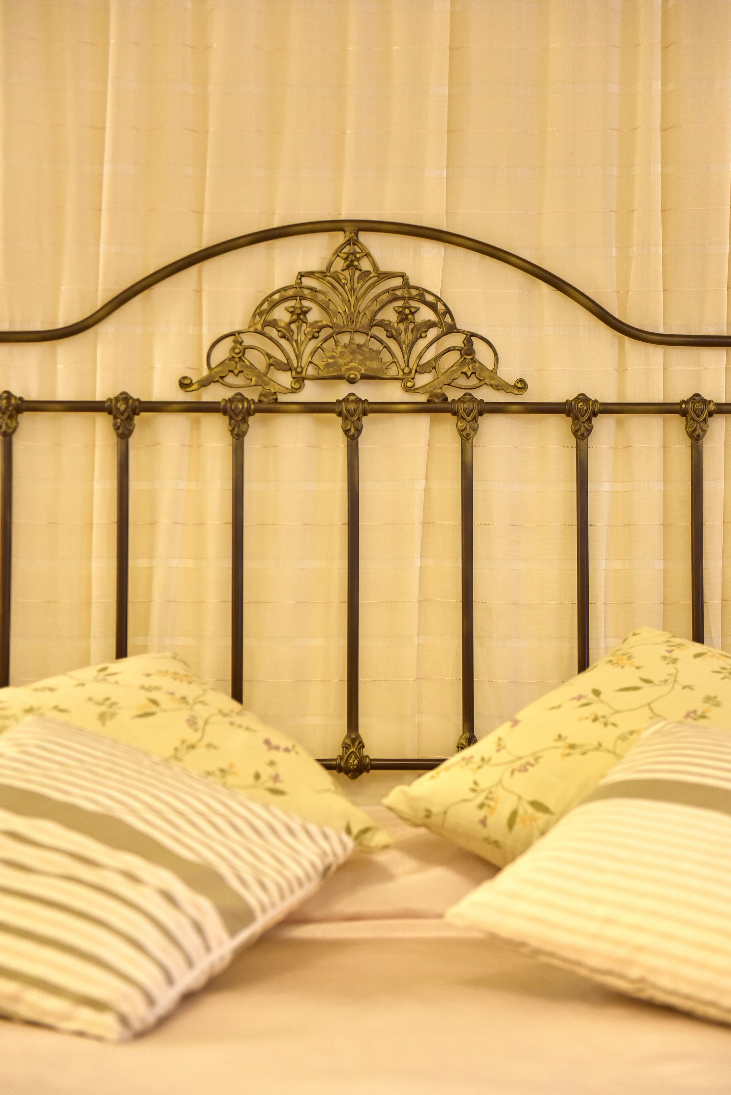 A bed with a metal headboard and floral-patterned pillows.