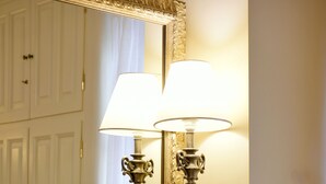 A bathroom with a large mirror, two wall-mounted lamps, and a wooden chair. - Angelica Boutique Hotel (Hydra)