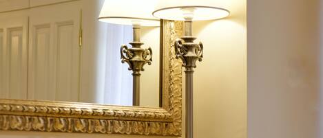A bathroom with a large mirror, two wall-mounted lamps, and a wooden chair.