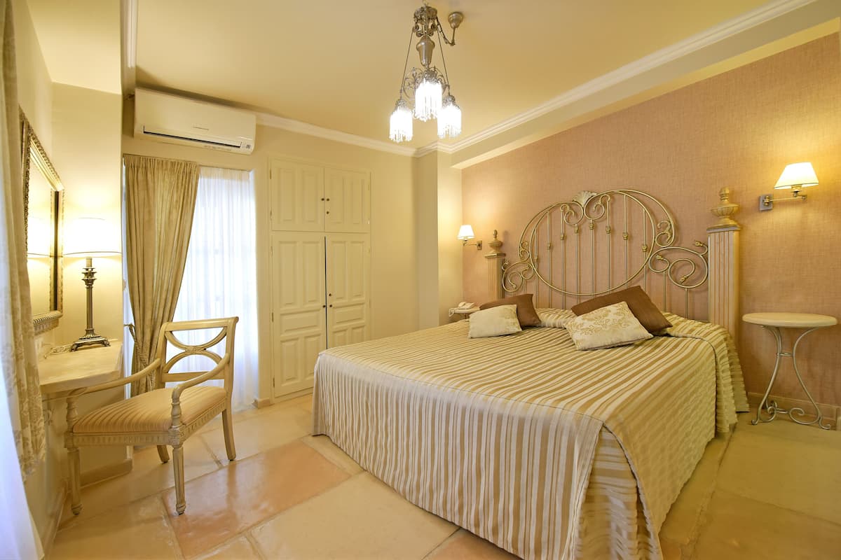 A bedroom with a bed, a chair, a desk, and a lamp.