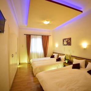 A hotel room with two beds, a flat-screen TV, a painting, and a nightstand with a vase. - Byzantion (Sparta)
