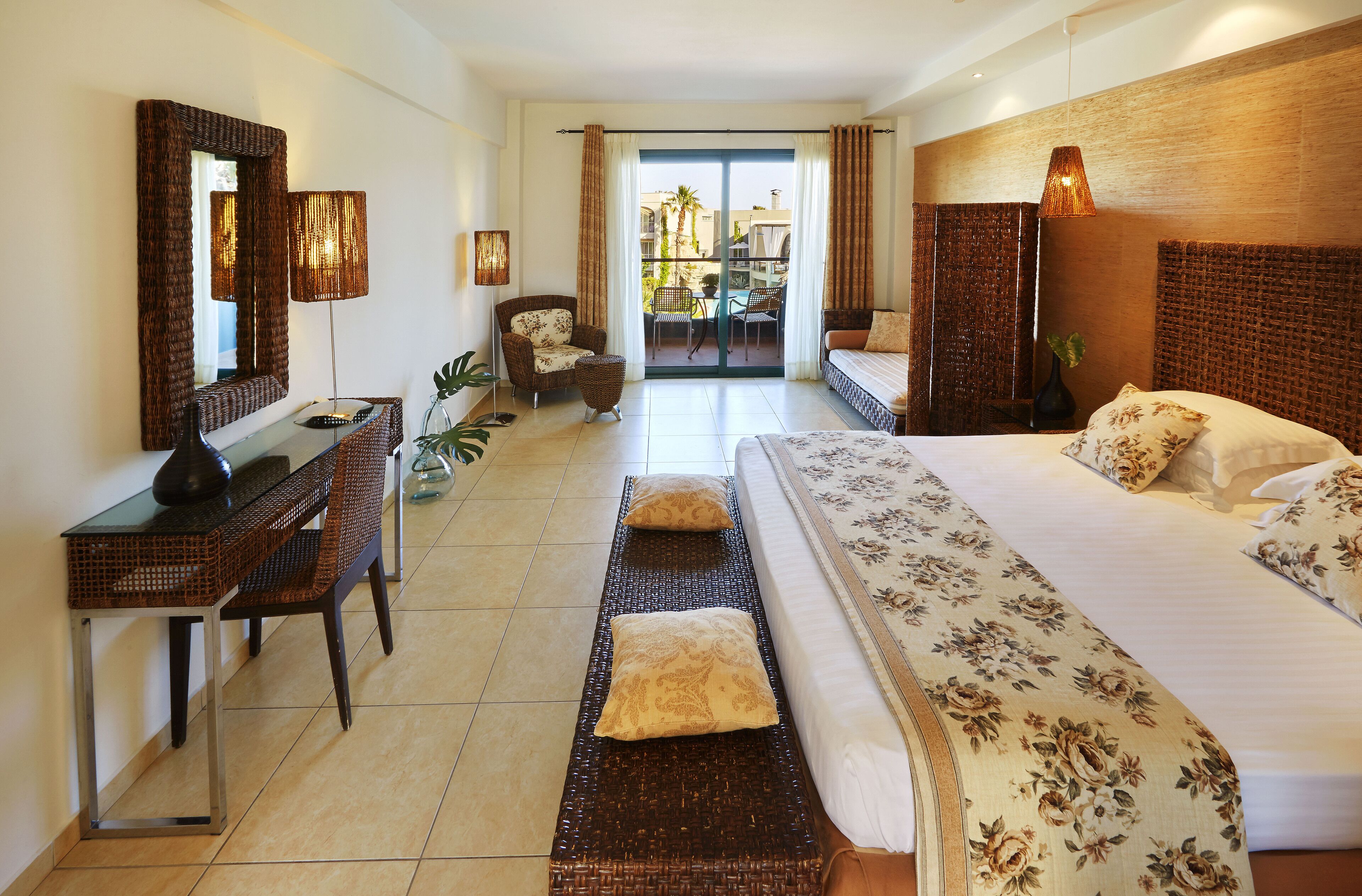 A hotel room with a bed, a desk, a chair, a small table, and a large mirror.