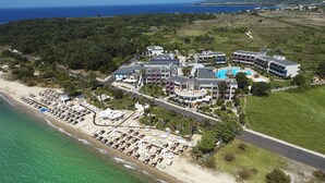 An aerial view of a coastal resort with a beach, multiple buildings, and a clear view of the ocean. - Ilio Mare Resort Hotel by GHH (Thasos)
